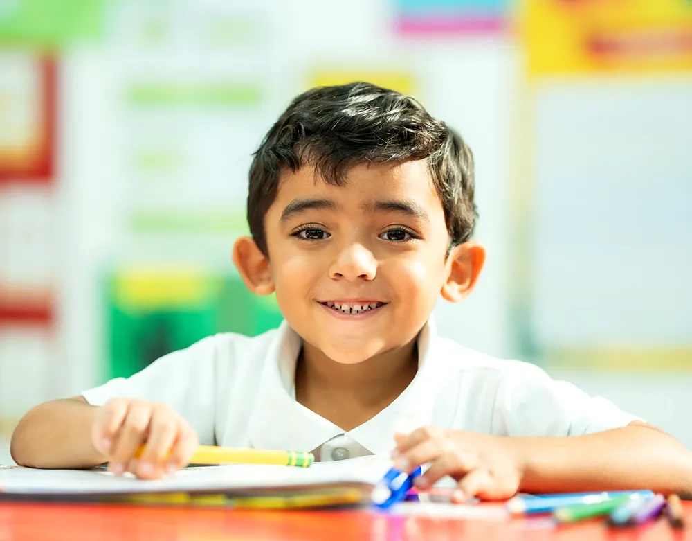 Niño de preescolar sonriendo en su mesa