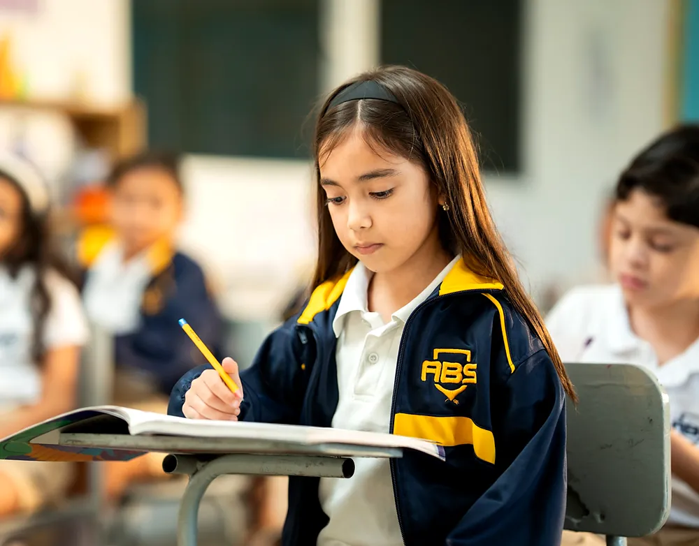 Estudiante de primaria escribiendo en su pupitre