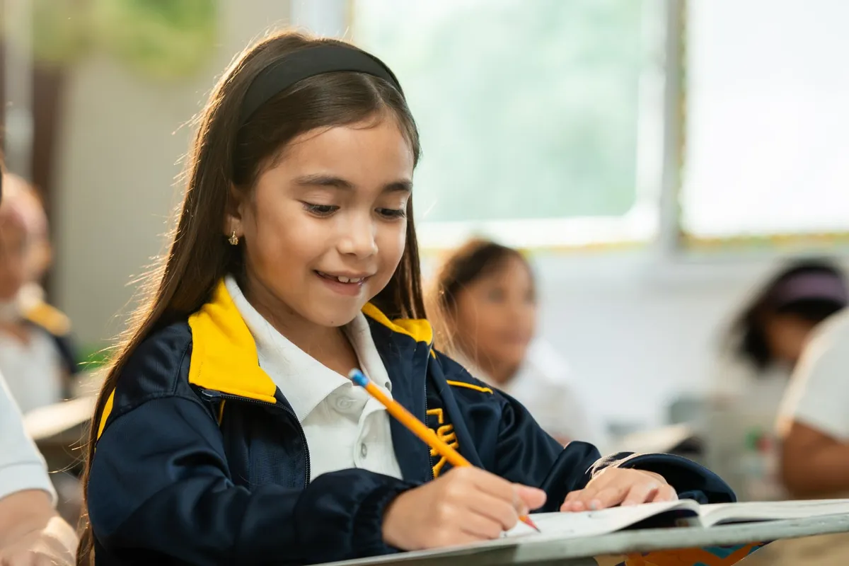 Estudiante de primaria escribiendo en su pupitre